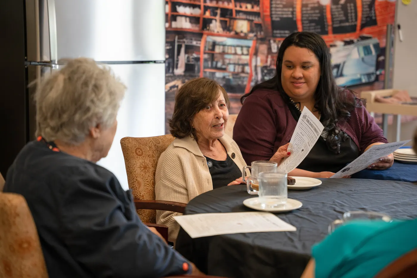 A resident and an associate reading the community newsletter together over coffee