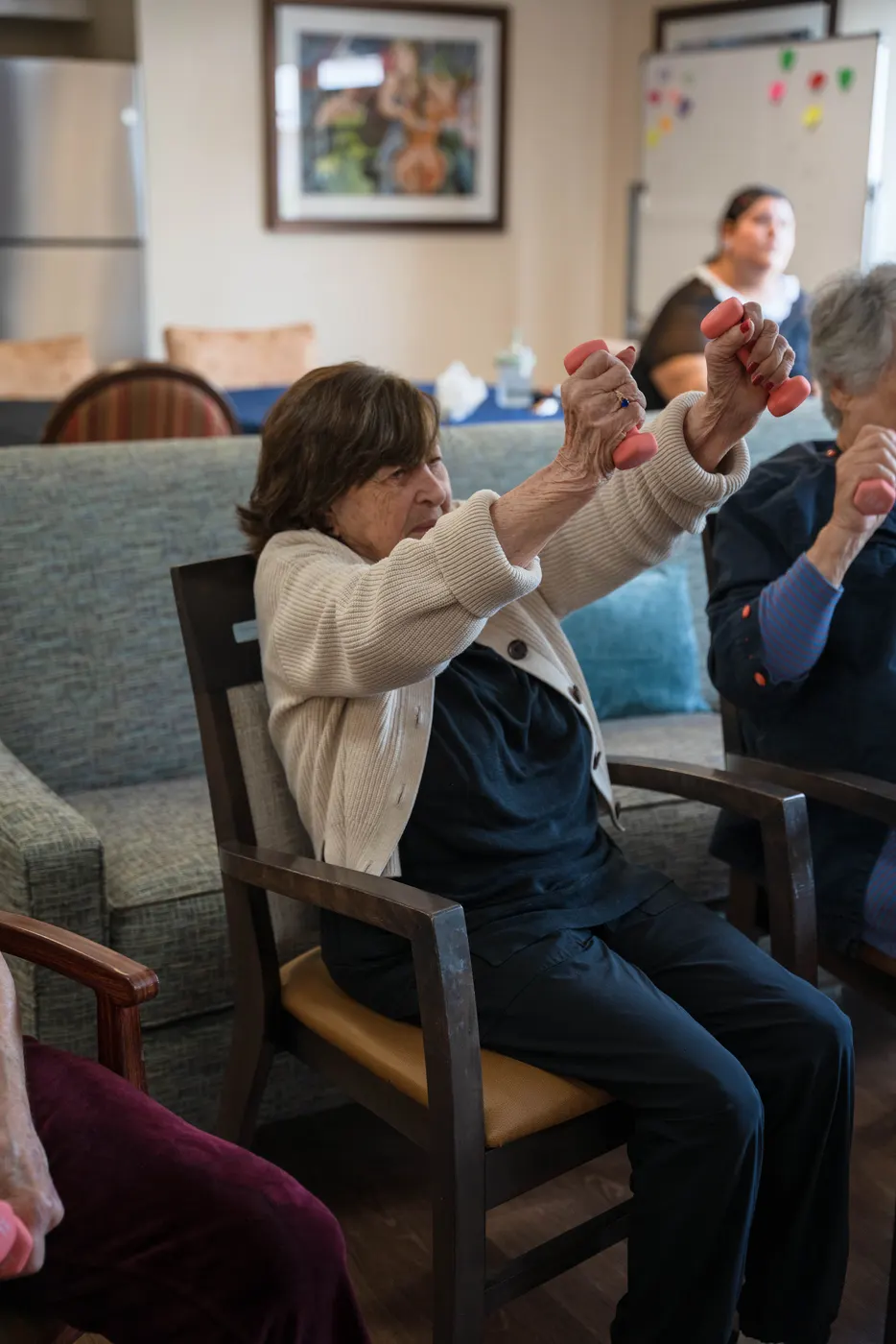 A resident lifting hand weights during the seated exercise class