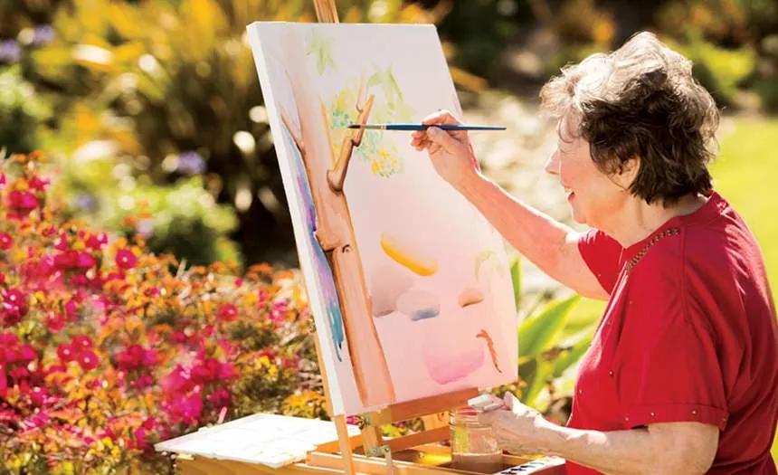 A resident painting at her easel in the garden