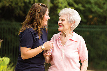 Resident walking outside laughing with caretaker