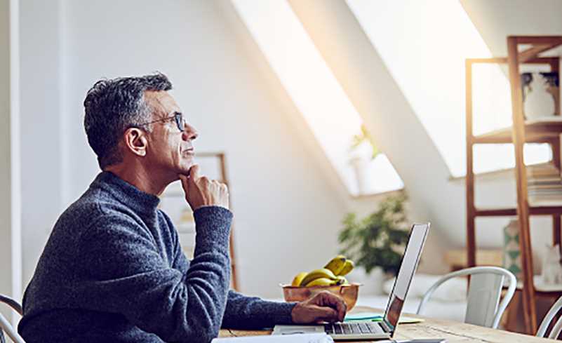 Elderly man thinking in front of laptop